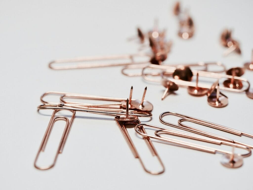 brass paper clip and push pin representing a type of fastener.