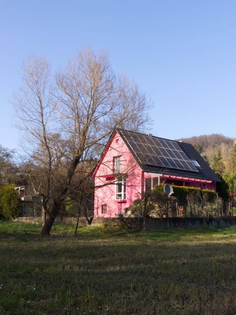 A red barn with black solar panels on the roof off the grid living.