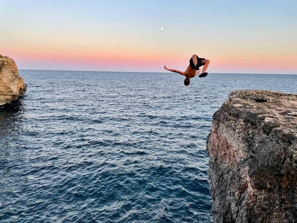 a person jumping off a cliff into the water