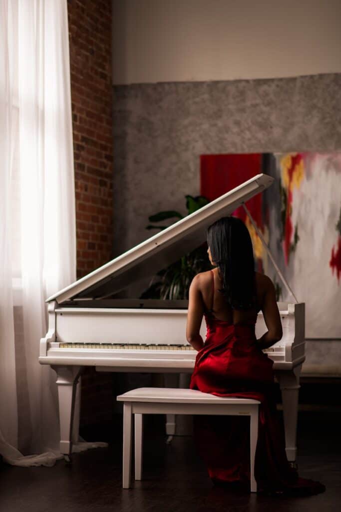 woman in red dress sitting on piano bench in front of a grand piano