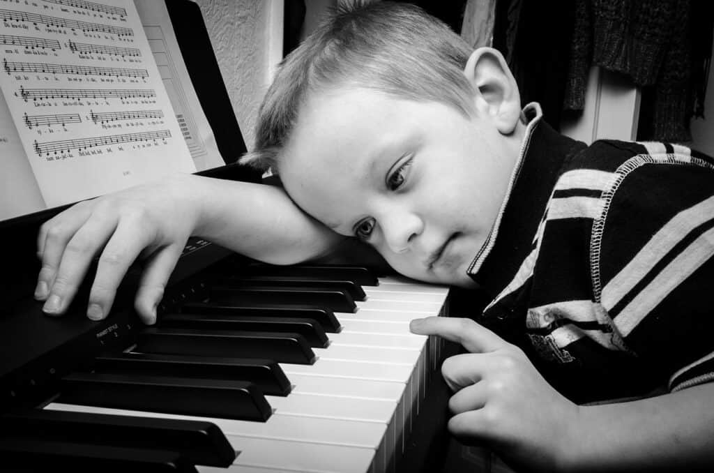 Boy leaning on piano at home.  