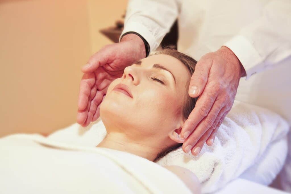 woman on reiki table hands on each side of woman's head